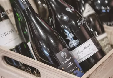 A wooden box full of wine bottles in various sizes and labels. The bottles are well organized and radiate an inviting atmosphere.