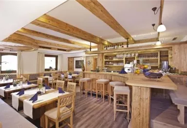 Ein gemütliches Restaurant mit Holzmöbeln und schön gedeckten Tischen. Große Fenster lassen viel Licht herein und schaffen eine einladende Atmosphäre.