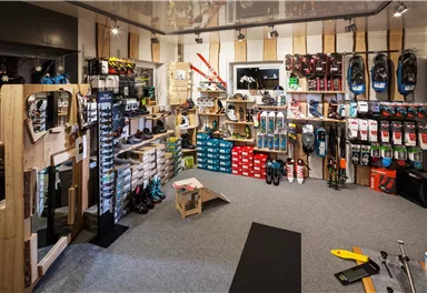 A sports store with a large selection of equipment and shoes.  
Shelves are filled with various brands and products.