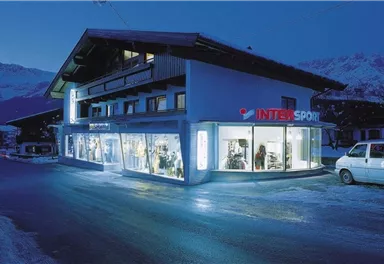 A sports store at night with illuminated windows. The building has a modern style and is surrounded by snow.