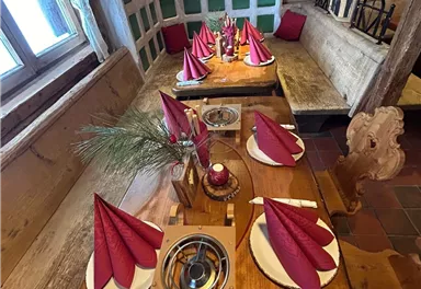 Ein rustikales Restaurant mit einem Holztablett, das elegant gedeckt ist. Rote Stoffservietten und Dekoration schaffen eine festliche Atmosphäre.