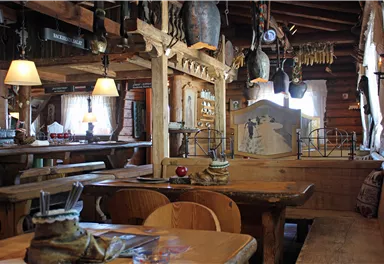 Ein gemütliches Restaurant mit rustikaler Holzdekor und warmem Licht. Die Tische sind ordentlich gedeckt, und die Atmosphäre ist einladend.