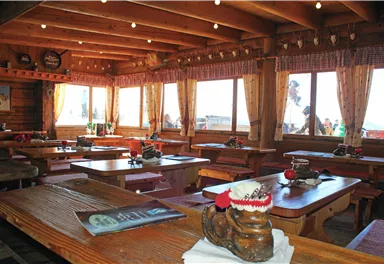 Ein gemütliches Restaurant mit Holztischen und Bänken. Große Fenster bieten einen Blick auf die schöne Landschaft.