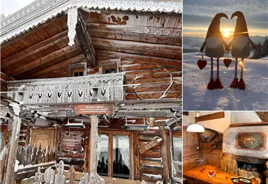 Ein charmantes, verschneites Holzhaus mit einem Balkon und gefrorenen Verzierungen. Im Bild sind auch zwei dekorative Figuren, die ein Herz halten, und eine gemütliche Inneneinrichtung zu sehen.
