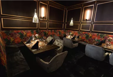 Ein elegantes Restaurant mit gemütlichen Sitzplätzen und stilvollen Tischdekorationen. Die Wände sind kunstvoll gestaltet und schaffen eine einladende Atmosphäre.