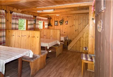 Gemütlicher Innenraum mit Holzvertäfelung und Tischen. Große Fenster lassen viel Tageslicht herein und verleihen dem Raum eine einladende Atmosphäre.