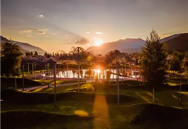 A beautiful sunset over a tranquil lake, surrounded by trees and mountains. The warm colors of the sky are reflected in the water.