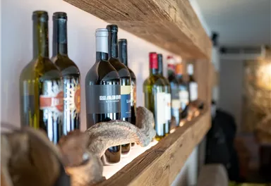 Eine Auswahl an Weinflaschen auf einem Holzregal. Die Flaschen sind ordentlich angeordnet und wirken einladend.