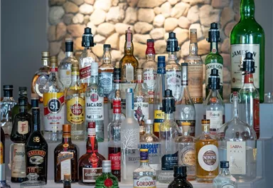 Eine Sammlung von verschiedenen Spirituosenflaschen auf einem Tisch. Die Flaschen sind bunt und vielfältig angeordnet.