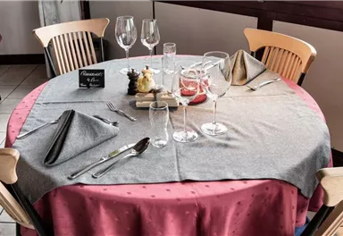 A beautifully set table in a restaurant with glassware and elegant table decoration. The tablecloth is gray with red accents.