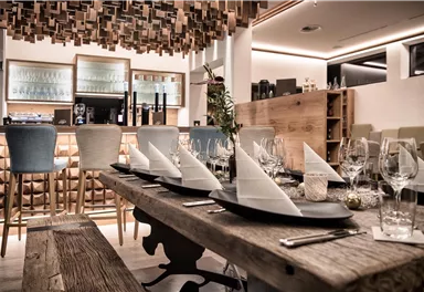 Ein elegantes Restaurant mit einer modernen Einrichtung. Der Tisch ist festlich gedeckt mit Gläsern und Servietten.