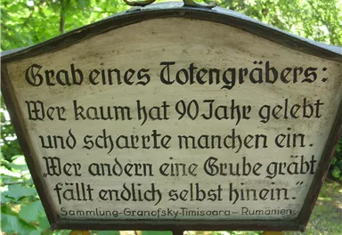 A writing on a wooden board outdoors. The text addresses life and death with a contemplative saying.