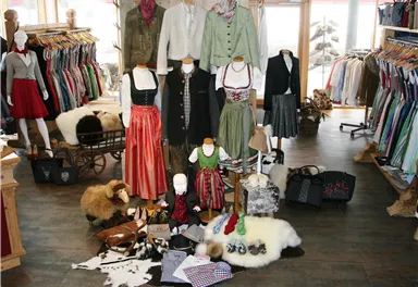 Eine modische Boutique mit traditioneller Kleidung und Accessoires. Verschiedene Trachten und Stoffe sind schön ausgestellt.