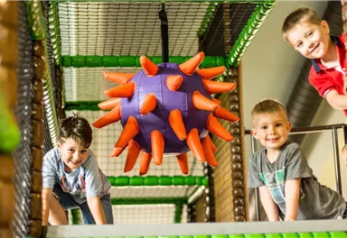 A play area for children with a large, spiky play ball. Two boys are having fun playing and exploring the climbing structures.