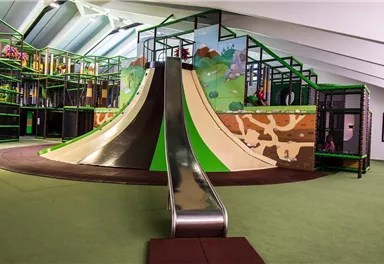 An exciting playground with a large slide and colorful walls. The area is designed in bright colors and offers plenty of space to play.