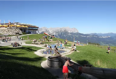A beautiful mountain area with play facilities for children. In the background, an impressive mountain landscape can be seen.
