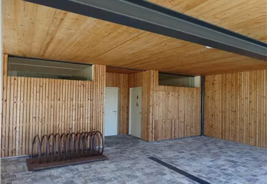 A modern room with wood paneling and a bright ceiling. On the left, there is a bike rack and two doors.