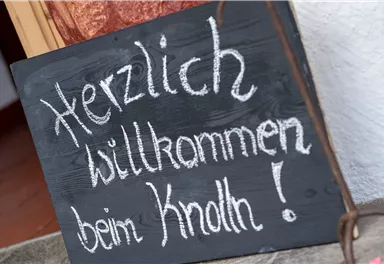 A welcome sign made of black chalkboard paint with the inscription "Warm welcome to Knoll!". It conveys an inviting atmosphere.