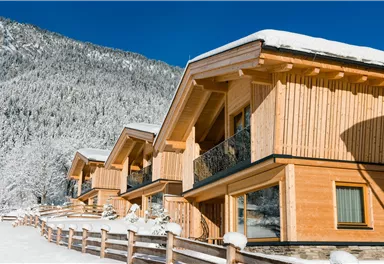 Beautiful wooden houses in a snowy landscape. The mountains in the background are covered with fresh snow.