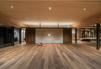 Ein moderner Raum mit Holzfußboden und weichen Beleuchtungselementen. An einer Wand befindet sich eine helle Steinoberfläche.