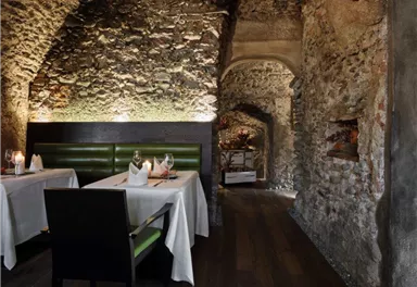 A stylish restaurant with rustic stone interior. Two set tables are situated in a cozy atmosphere.