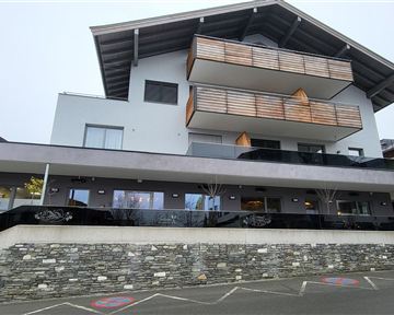 A modern building with several balconies and a tasteful design. The front is designed to be stylish and inviting.