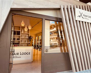 A modern hair salon named "Hair Lodge" in Ellmau. The entrance door is inviting and showcases a bright, minimalist interior.