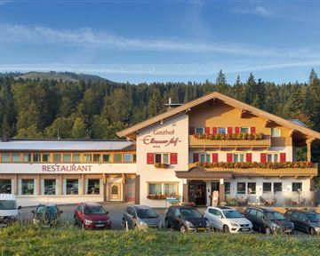 An inviting inn with a restaurant in a rural setting. The building is surrounded by trees and offers a beautiful view of the mountains.