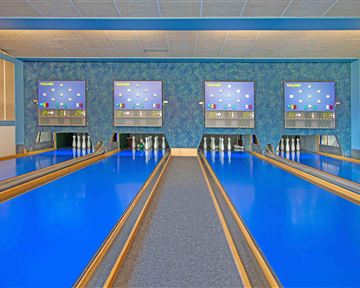 Eine Bowlingbahn mit leuchtenblauen Bahnen und digitalen Anzeigetafeln. Der Raum ist hell und modern gestaltet.