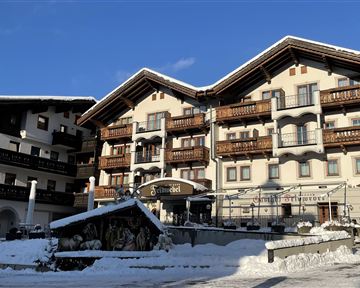 Ein gemütliches Hotel in den Bergen, umgeben von Schnee. Der klare Himmel und die alpine Architektur schaffen eine einladende Atmosphäre.