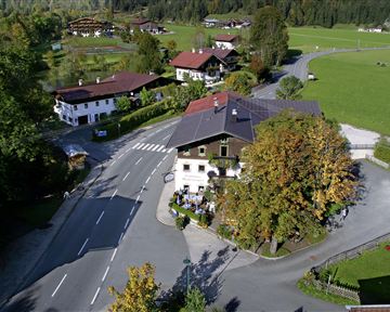 A picturesque village view with traditional houses and a quiet street. The surroundings are green and surrounded by trees.