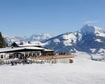 A cozy restaurant in the mountains, surrounded by snow-capped peaks. Skiers and visitors enjoy the view of the picturesque winter landscape.