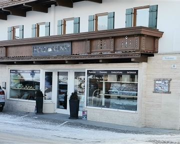 A cozy shop with an inviting display window. Above it is a wooden balcony with classic windows.