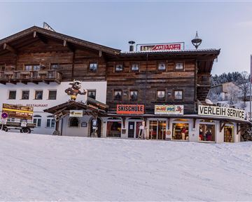Ein typisches Berghaus in einem winterlichen Skigebiet. Es gibt Geschäfte für Skiausrüstung und einen Skischul-Service.