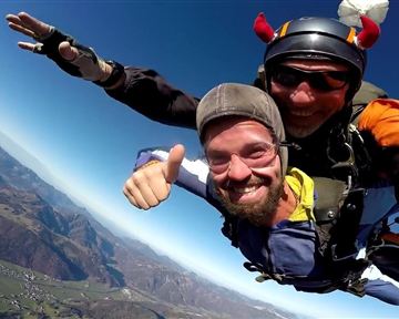 A brave tandem jump with a joking skydiver. In the background, the impressive mountain landscapes are visible.