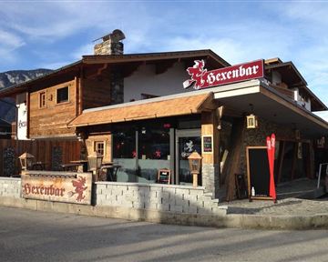 A charming wooden house named "Hexenbar". It is an inviting location with an attractive terrace and rustic ambiance.