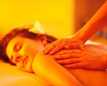 A relaxing massage in warm, gentle light. A woman is enjoying the treatment and looks very relaxed.