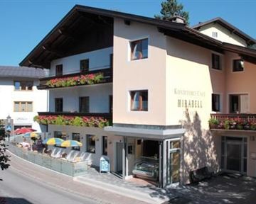 Ein gemütliches Café mit Blumenbalkonen und sonnigen Terrassen. Die Umgebung ist malerisch und einladend.