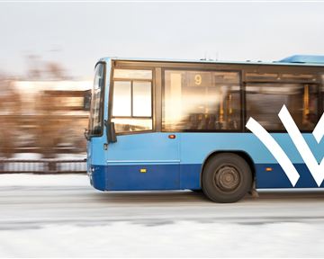 Ein blauer Bus fährt auf einer verschneiten Straße. Die Anzeige zeigt die Linie 9.
