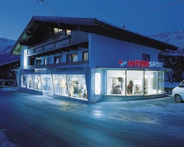 A sports store at night with illuminated windows. The building has a modern style and is surrounded by snow.
