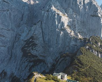 An impressive mountain landscape with steep rocks and a beautiful meadow in the foreground. In the background, the rock rises majestically.