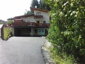 Ein modernes Haus mit einem Balkon und einer Auffahrt. Umgeben von Bäumen in einer ruhigen Umgebung.