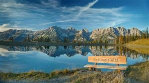 A tranquil lake with impressive mountains in the background. A cozy bench with the inscription "Ereblingsplätzl" invites you to linger.