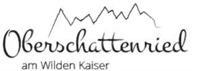 A stylized logo of "Oberschattenried am Wilden Kaiser". It features a mountain silhouette above the lettering.