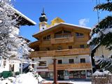 A beautiful building in alpine style, surrounded by snow-covered trees. The clear blue sky completes the winter landscape.