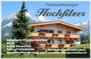 Ein charmantes Ferienhaus mit Balkon, umgeben von Bäumen und Bergen. Die Umgebung ist grün und einladend, ideal für einen Urlaub in den Tiroler Alpen.