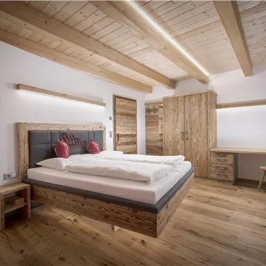 Ein modernes Schlafzimmer mit Holzmöbeln und einem großen Bett. Der Raum hat helle Wände und eine angenehme Atmosphäre.