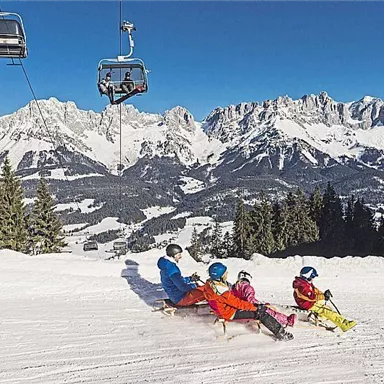 An idyllic winter landscape with snowy mountains. A family enjoys skiing in the sun.