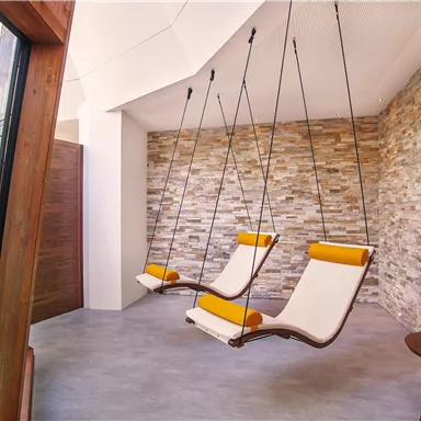 A modern room with hanging chairs and a stylish stone wall. The room has a bright and relaxing atmosphere.
