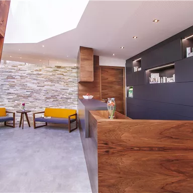 A modern reception area with wood and stone elements. Comfortable seating and a bright, inviting atmosphere.